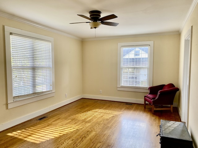 living area with ornamental molding, light wood-type flooring, and ceiling fan