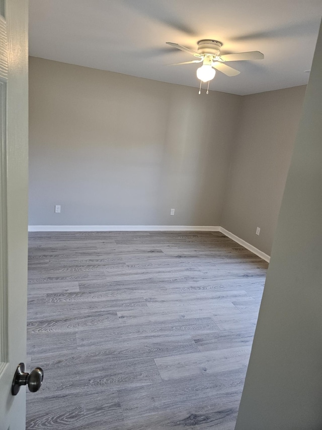 empty room with ceiling fan and light hardwood / wood-style flooring