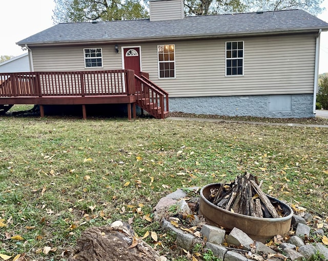 rear view of property featuring a lawn, a deck, and an outdoor fire pit