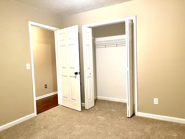 unfurnished bedroom with light colored carpet, a textured ceiling, and a closet