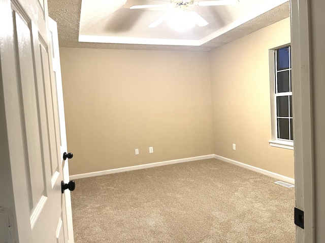 unfurnished room with carpet floors, a textured ceiling, and a tray ceiling