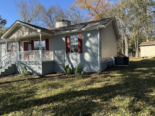 view of front of home featuring a porch, a storage unit, a front yard, and central air condition unit