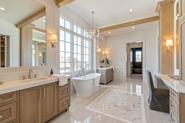 bathroom with a freestanding tub, beamed ceiling, two vanities, and a sink