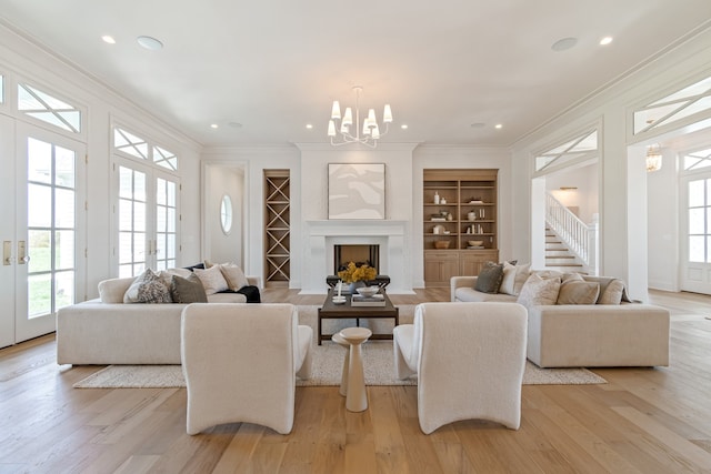 living room with light wood-type flooring, a fireplace, crown molding, and french doors