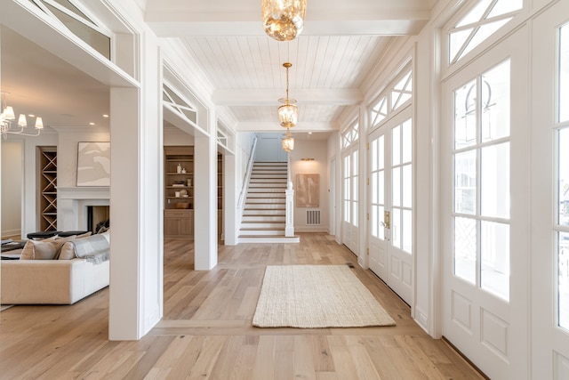 entrance foyer with a notable chandelier, visible vents, stairway, light wood-style floors, and beamed ceiling