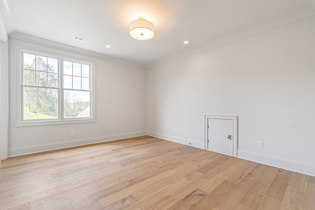 spare room with light wood finished floors, recessed lighting, visible vents, ornamental molding, and baseboards