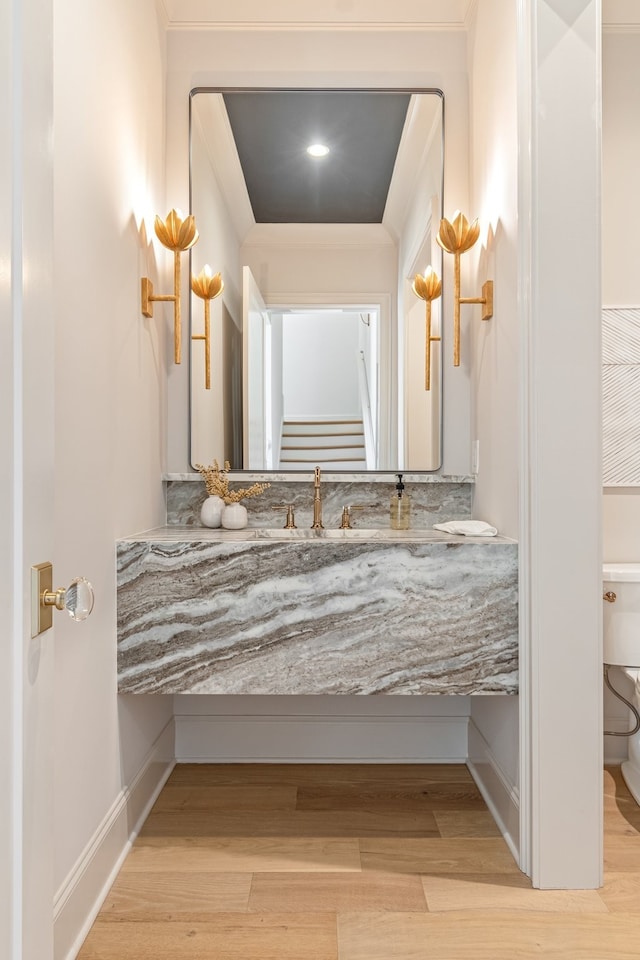 bathroom with toilet, ornamental molding, wood finished floors, and vanity