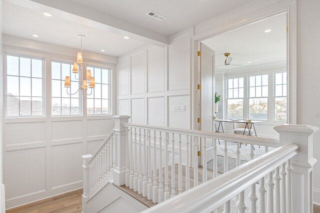 staircase with recessed lighting, visible vents, a decorative wall, and wood finished floors