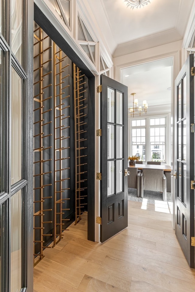 wine cellar featuring light wood-type flooring, an inviting chandelier, and ornamental molding