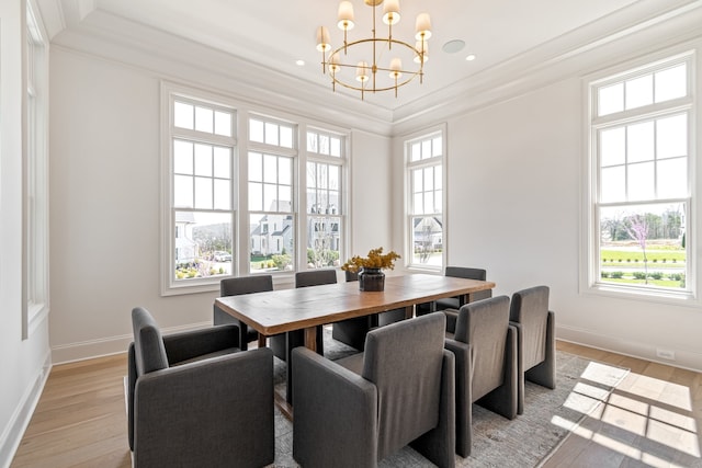 dining room featuring light wood-type flooring, baseboards, ornamental molding, and a chandelier