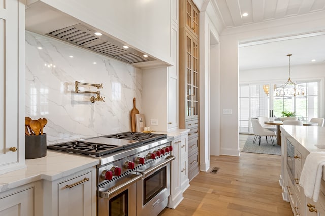 kitchen with white cabinets, light stone countertops, custom exhaust hood, light wood-style floors, and double oven range