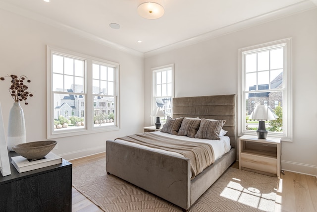 bedroom with light wood-style flooring, ornamental molding, and baseboards