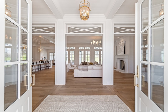 foyer featuring a chandelier, ornamental molding, beam ceiling, and french doors