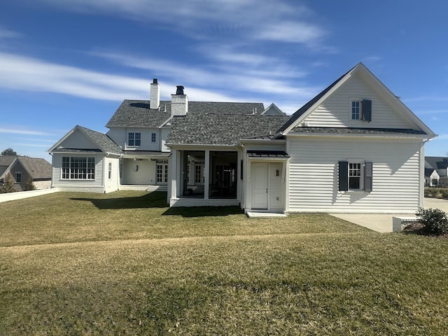 rear view of house featuring a standing seam roof, a yard, a chimney, and metal roof