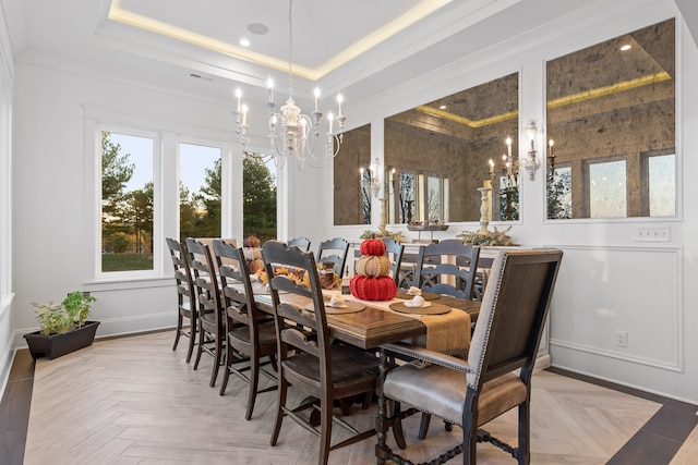 dining area with a chandelier, a raised ceiling, and light parquet floors