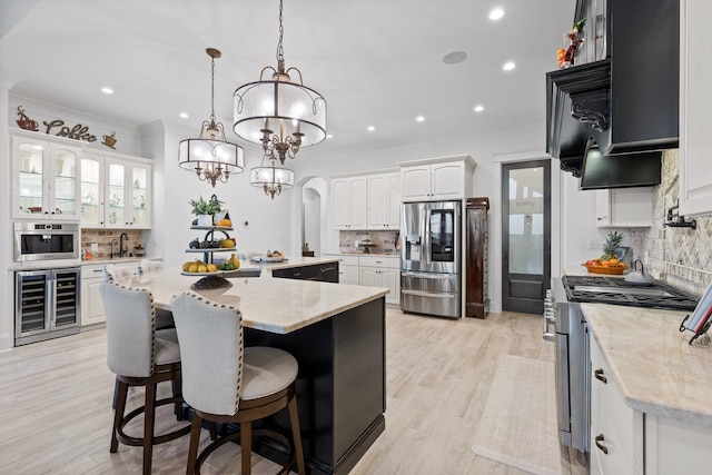 kitchen featuring wine cooler, appliances with stainless steel finishes, a kitchen island, white cabinets, and decorative backsplash