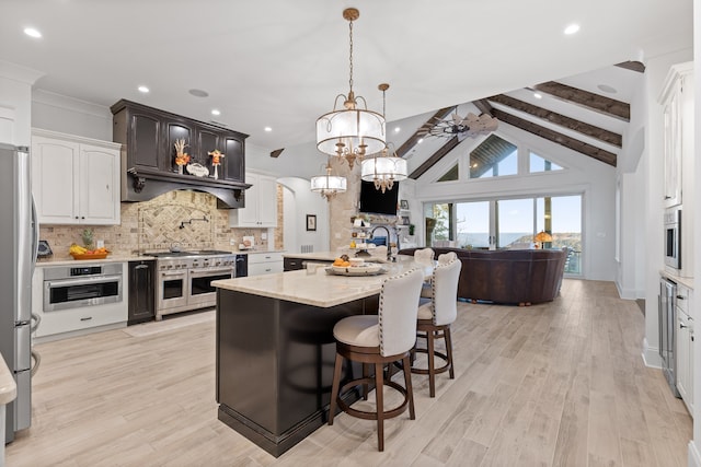 kitchen featuring stainless steel appliances, light hardwood / wood-style floors, vaulted ceiling with beams, pendant lighting, and decorative backsplash