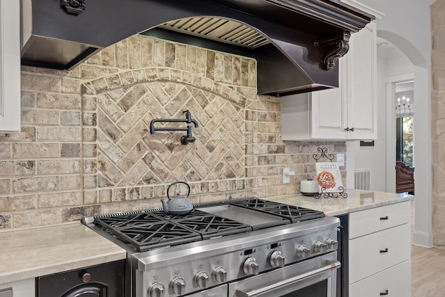 kitchen featuring tasteful backsplash, premium range hood, white cabinetry, light wood-type flooring, and stainless steel range