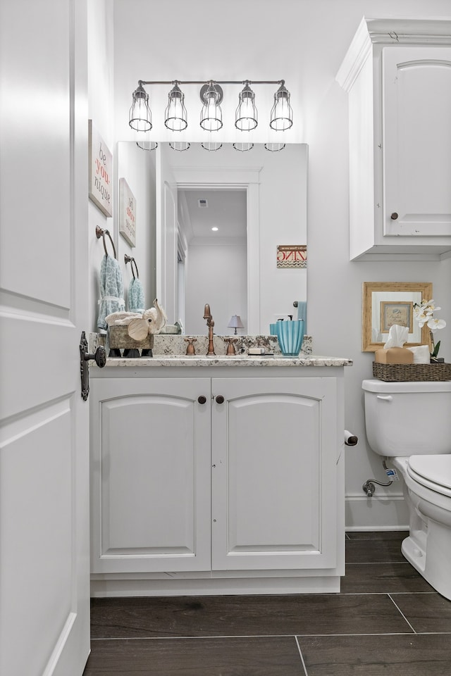 bathroom with toilet, vanity, and hardwood / wood-style floors