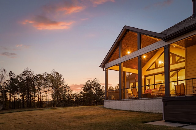 property exterior at dusk featuring a lawn