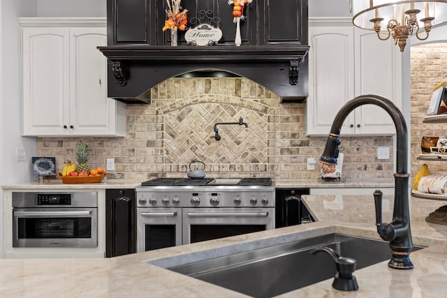 kitchen featuring light stone counters, white cabinetry, backsplash, and appliances with stainless steel finishes