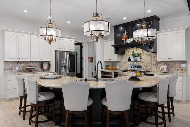 kitchen with a large island, white cabinetry, stainless steel fridge with ice dispenser, and light hardwood / wood-style floors