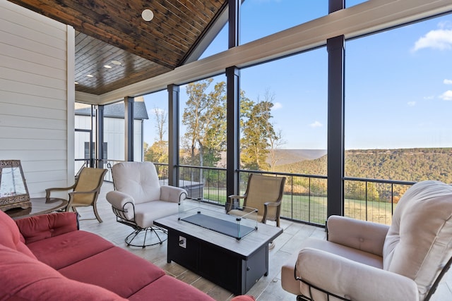 sunroom / solarium featuring a mountain view, lofted ceiling, and wood ceiling