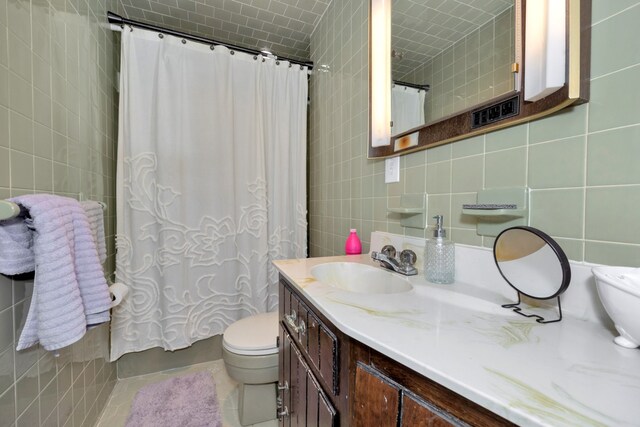 bathroom with toilet, tile patterned floors, tile walls, decorative backsplash, and vanity