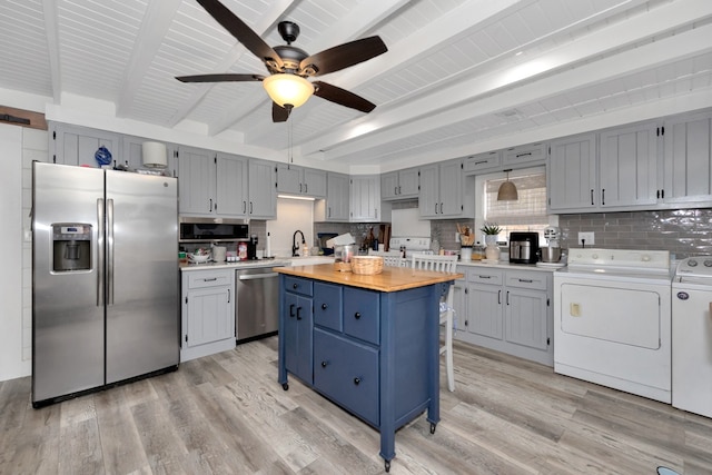 kitchen featuring stainless steel appliances, beamed ceiling, light hardwood / wood-style flooring, washing machine and dryer, and wood counters