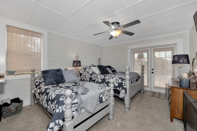 carpeted bedroom with wood walls, ceiling fan, french doors, and access to outside