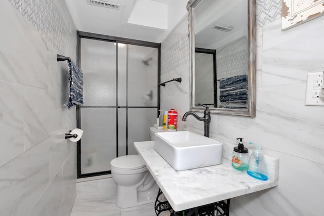 bathroom with sink, an enclosed shower, tile walls, and toilet