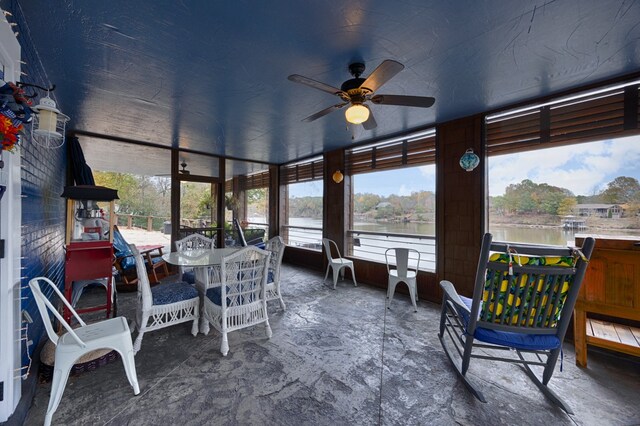 sunroom with a wealth of natural light, a water view, and ceiling fan