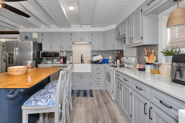 kitchen featuring gray cabinetry, tasteful backsplash, stainless steel appliances, light wood-type flooring, and sink