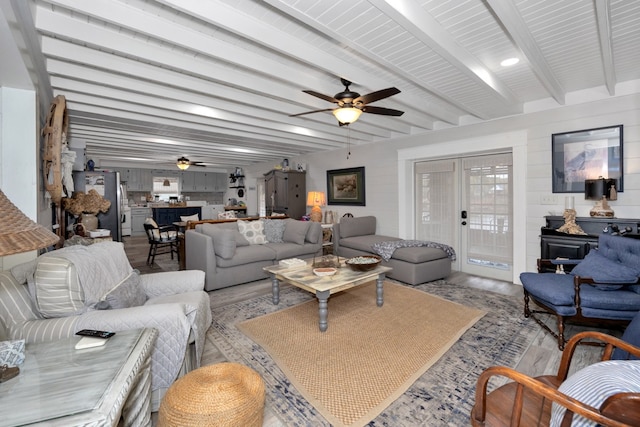 living room with ceiling fan, beam ceiling, and light wood-type flooring