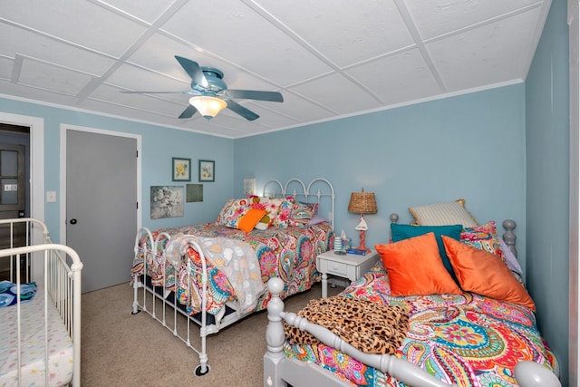 carpeted bedroom featuring ceiling fan and a paneled ceiling