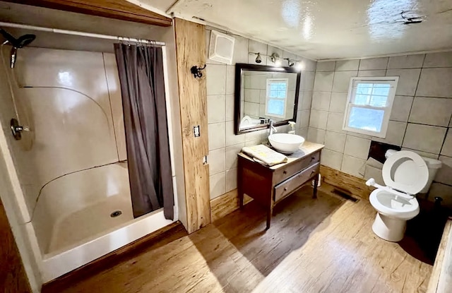 bathroom featuring toilet, tile walls, hardwood / wood-style floors, vanity, and a shower with shower curtain