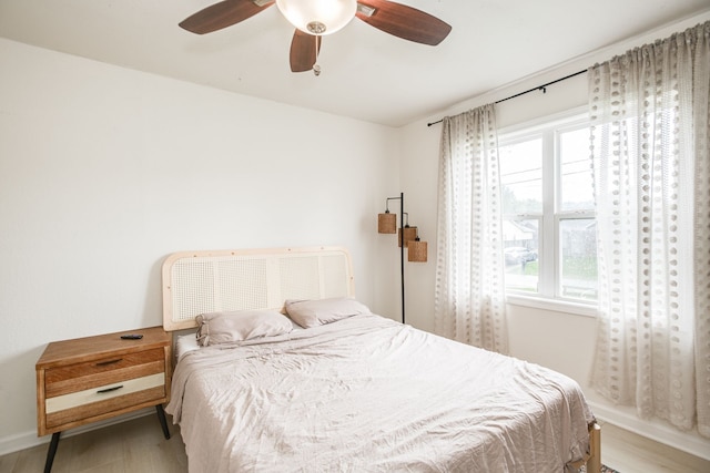 bedroom featuring ceiling fan, multiple windows, and light hardwood / wood-style floors