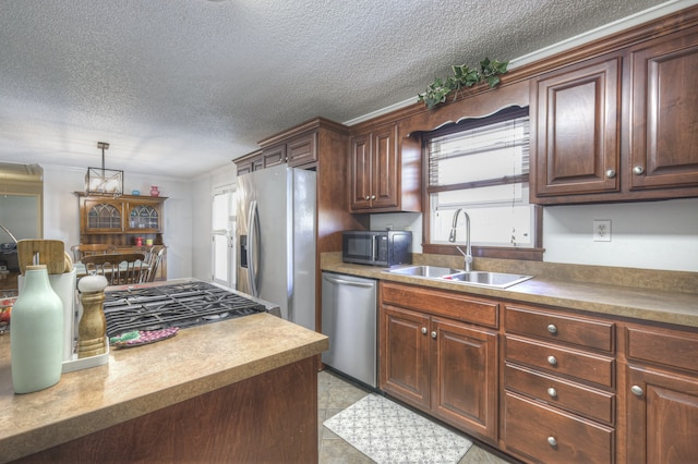 kitchen featuring a textured ceiling, appliances with stainless steel finishes, hanging light fixtures, and sink