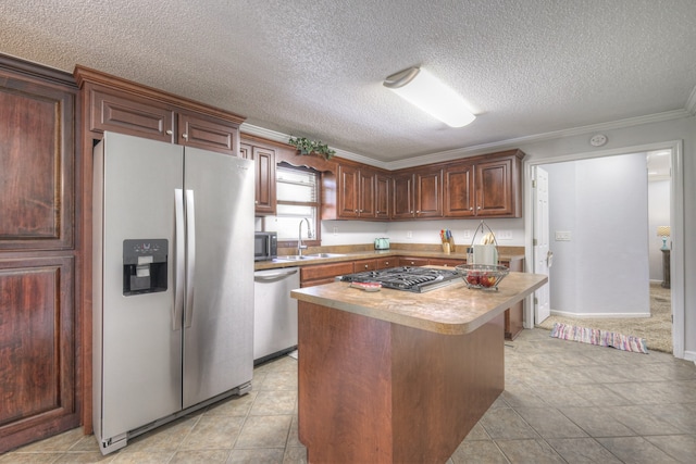 kitchen with stainless steel appliances, sink, a textured ceiling, crown molding, and a kitchen island