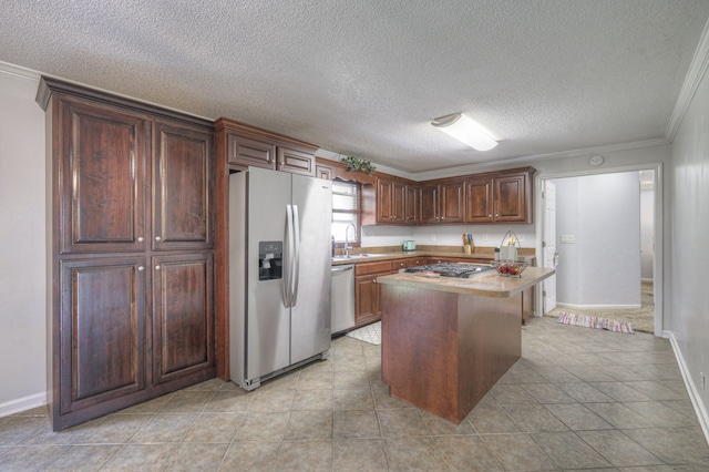 kitchen with ornamental molding, a kitchen island, appliances with stainless steel finishes, a textured ceiling, and sink