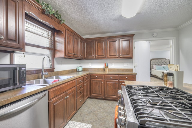 kitchen with a textured ceiling, sink, ornamental molding, and stainless steel appliances