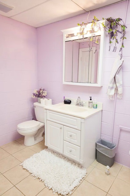 bathroom featuring toilet, tile walls, vanity, and tile patterned floors