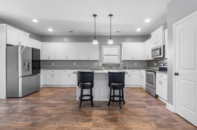 kitchen featuring pendant lighting, stainless steel appliances, white cabinetry, and dark hardwood / wood-style floors