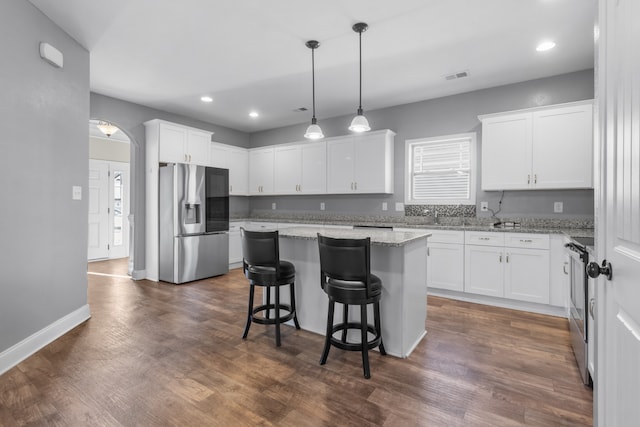 kitchen featuring dark wood-type flooring, a center island, white cabinets, and stainless steel appliances