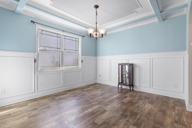 spare room featuring coffered ceiling, dark hardwood / wood-style floors, crown molding, and an inviting chandelier