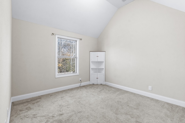 carpeted spare room with lofted ceiling