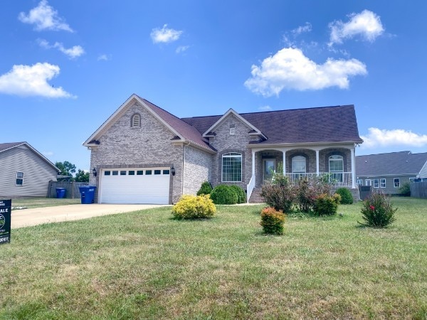 single story home with covered porch, a garage, and a front yard