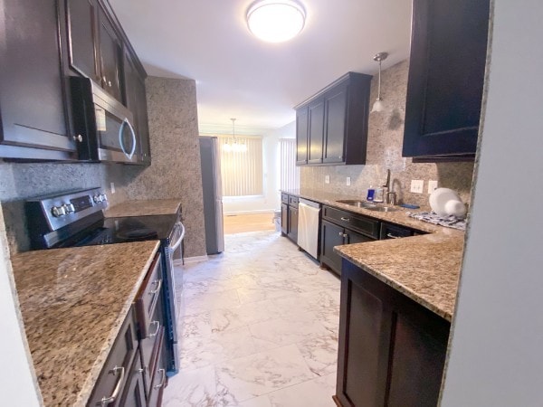 kitchen with appliances with stainless steel finishes, dark brown cabinets, pendant lighting, light stone countertops, and sink