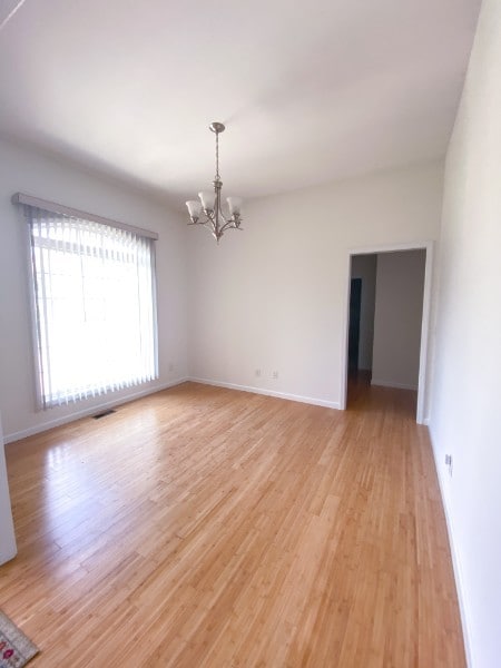 unfurnished room featuring light wood-type flooring and a notable chandelier