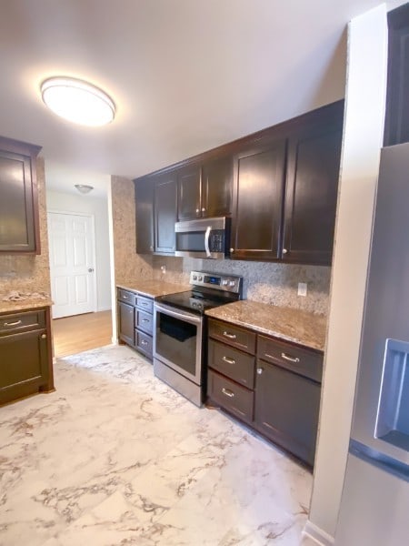 kitchen with stainless steel appliances, dark brown cabinets, and tasteful backsplash